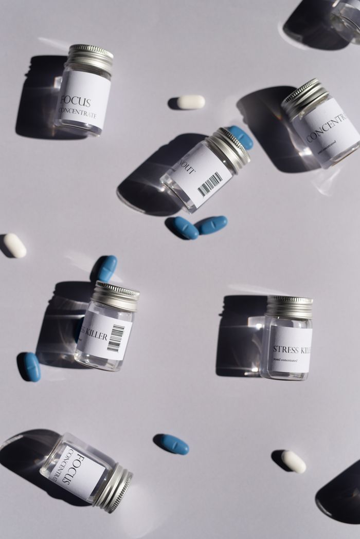 Home Artistic flat lay of medicine bottles and pills against a white background, casting shadows.
