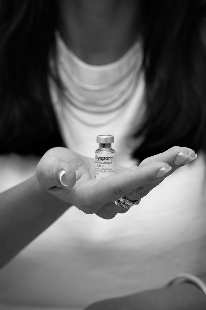 Monochrome photo of a person holding a Dysport vial, focusing on wellness.