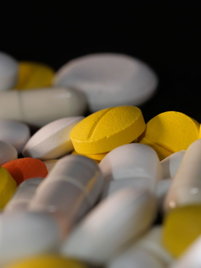 Contact Close-up of various colored pills and capsules against a dark backdrop.