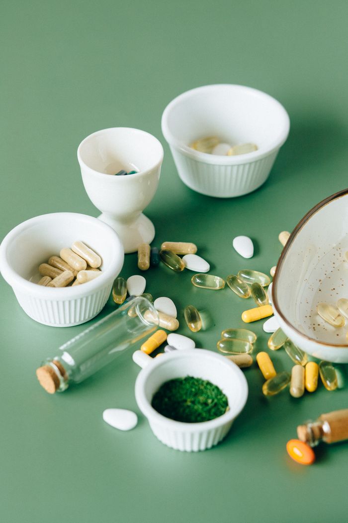 Home Assorted natural supplements and pills in ceramic bowls on a green background, showcasing health and wellness themes.